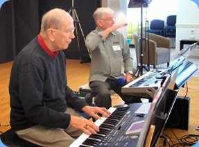 John Beales playing his Korg Pa500 with Gordon Sutherland in the background checking the PA sound level. Photo courtesy of Dennis Lyons.