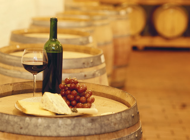 wine bottle with a wine glass and cheese on a barrel --- Image by © Royalty-Free/Corbis