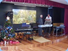 Preparing the stage for the evening's entertainment. Peter Brophy talks with Kevin Johnston. The oil painting in the background had arrived earlier that day for mounting. The painting depicts a scene north of Orewa and was painted by our multi-talented member, John Perkin.