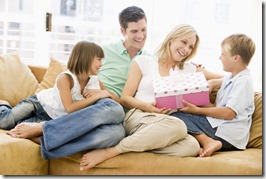 Family in living room with mother receiving gift and smiling