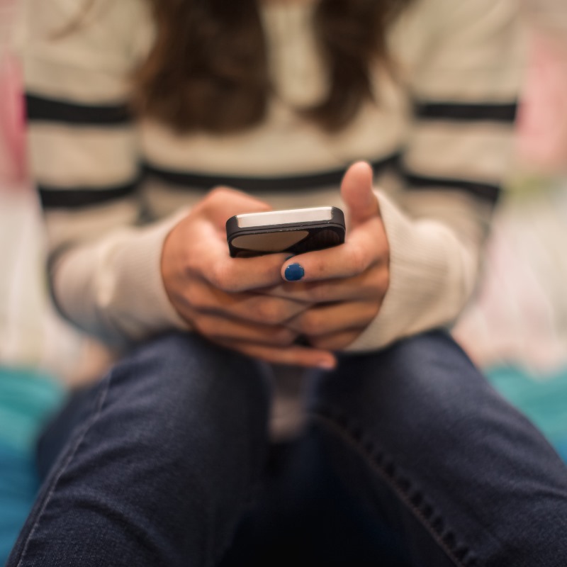 Close up of teenage girl texting on mobile in bedroom