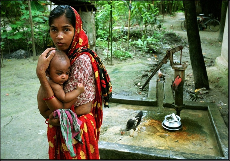 BANGLADESH. Khulna. Jessore. Jhikargachha village. A woman whose arms and sides show the telltale black marks of arsenic poisoning has only this pump for fresh water.2000.