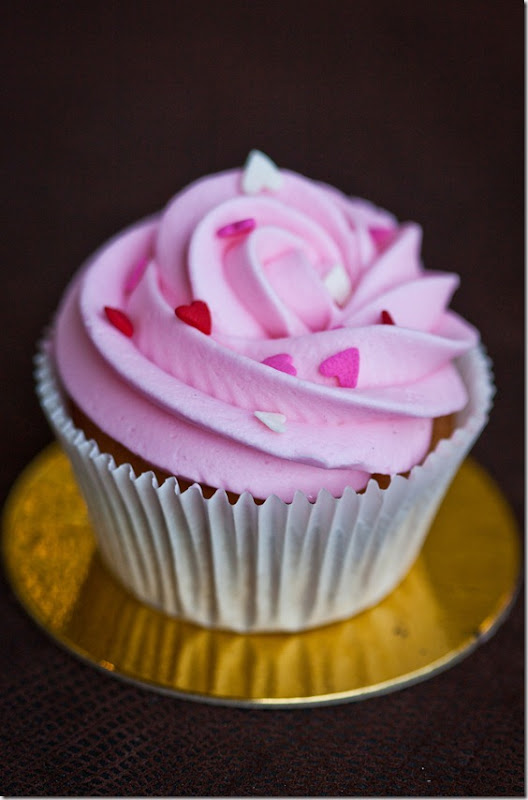 Vanilla cupcake with pink frosting and heart sprinkles. 