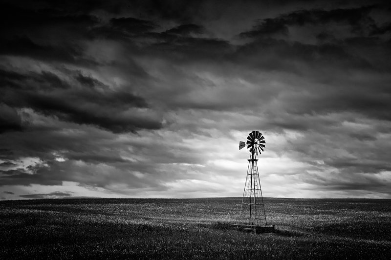 A majestic windmill stand tall undr a stormy sky north of Cochrane