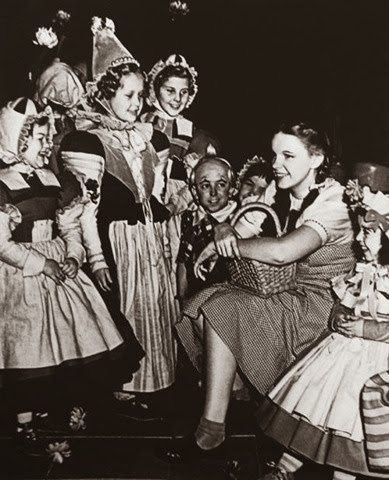 Judy Garland hangs out with the Munchkins while taking a break from filming the Wizard of Oz
