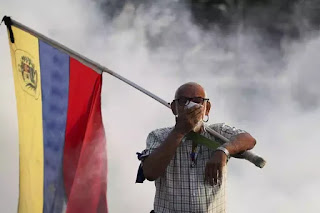 Người già Venezuela cũng xông pha trong hơi khói của lựu đạn cay. Người già Venezuela cũng xông pha trong hơi khói của lựu đạn cay.