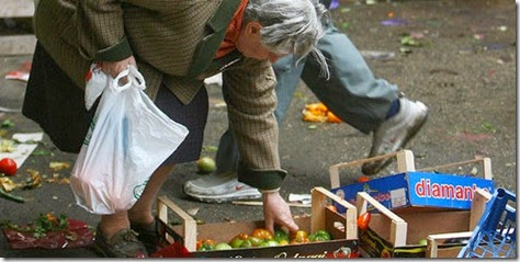 Una signora anziana povera che rovista una cassa di ortaggi (foto Caltagirone)
