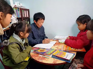 Thầy giáo làng Bùi Văn Đông hướng dẫn các em học sinh đọc sách.