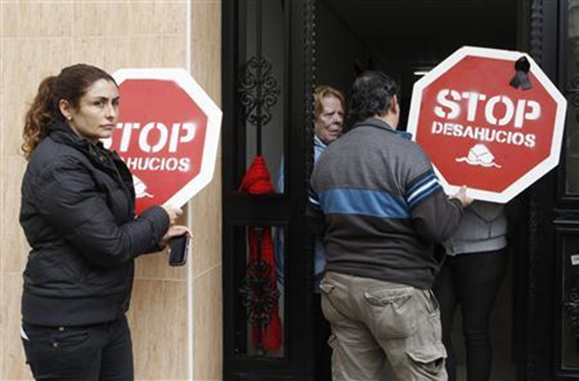 Members of the Stop Evictions movement enter the home of Gisela Bajo (unseen) as they wait for the judicial commission to evict her from her home in Valencia, 15 November 2012. Bajo, mother of a 13-year-old daughter, is unemployed and has no income. Spain's main political parties started negotiations about eviction law reform on Monday after a homeowner's suicide provoked public fury and accusations that politicians and banks are complicit in de facto 'murder'. The signs read, 'Stop evictions'. Heino Kalis / REUTERS