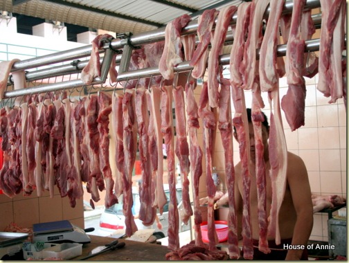 fresh pork belly strips hanging at the market