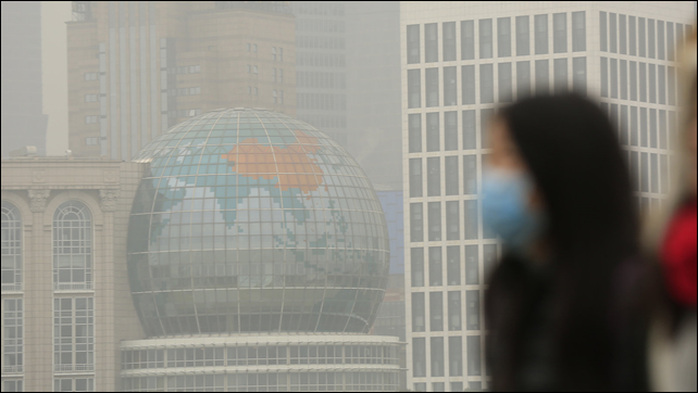 A woman wears a face mask on a hazy day in downtown Shanghai, in January 2015. China has ordered a popular anti-pollution film, 'Under the Dome', removed from major online outlets. In Xi'an, two people who had protested against smog were reportedly detained on 9 March 2015. Photo: ALY SONG / Reuters / Landov