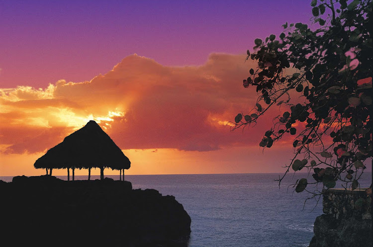 A hut is framed against an orange sunset in Jamaica. 