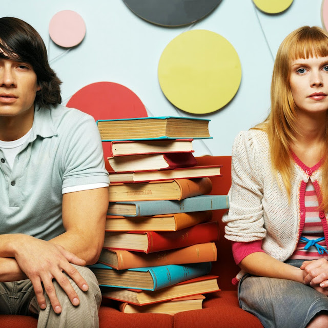 Young Couple Sitting with a Pile of Books --- Image by © Royalty-Free/Corbis