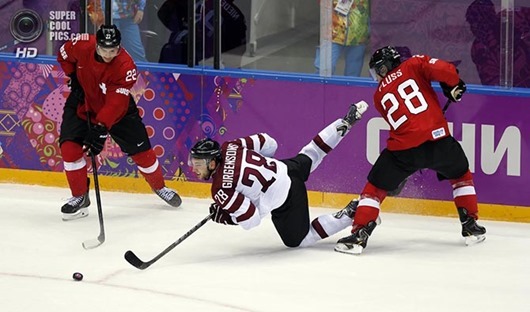 Feb 18, 2014; Sochi, RUSSIA; Latvia forward Zemgus Girgensons (28) loses his balance as he reaches for the puck between Switzerland forward Martin Pluss (28) and forward Nino Niederreiter (22) in a men's ice hockey playoffs qualifications game during the Sochi 2014 Olympic Winter Games at Bolshoy Ice Dome. Mandatory Credit: Winslow Townson-USA TODAY Sports