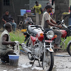 A droite, un motard récupère son véhicule lavé, prêt à affronter sa nouvelle journée de travail.
