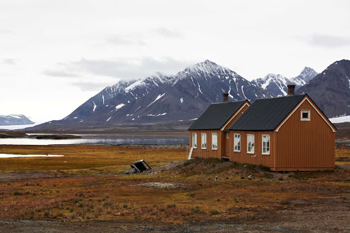 Svalbard-mountains-and-house - Revel in the peacefulness of the Svalbard Islands as you explore the region aboard the Hurtigruten Fram.