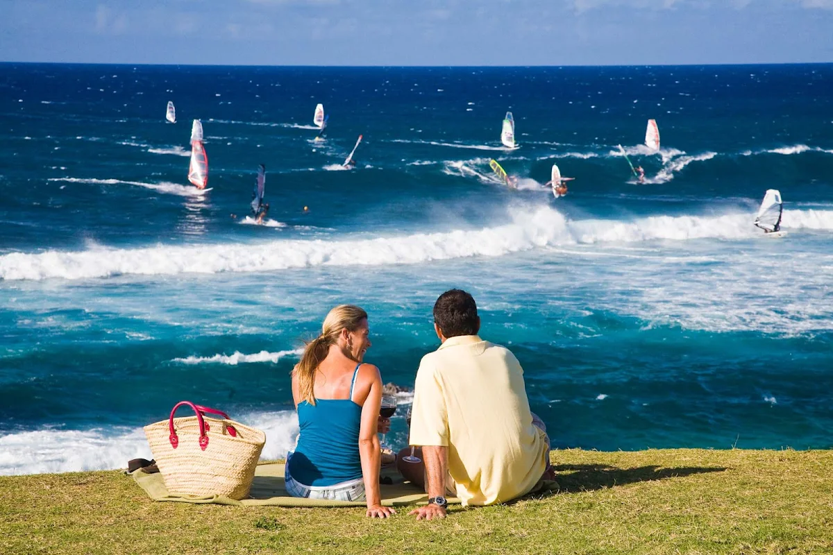 windsurfers-Maui - A couple enjoys a picnic while watching windsurfers in Lower Paia, Maui. 