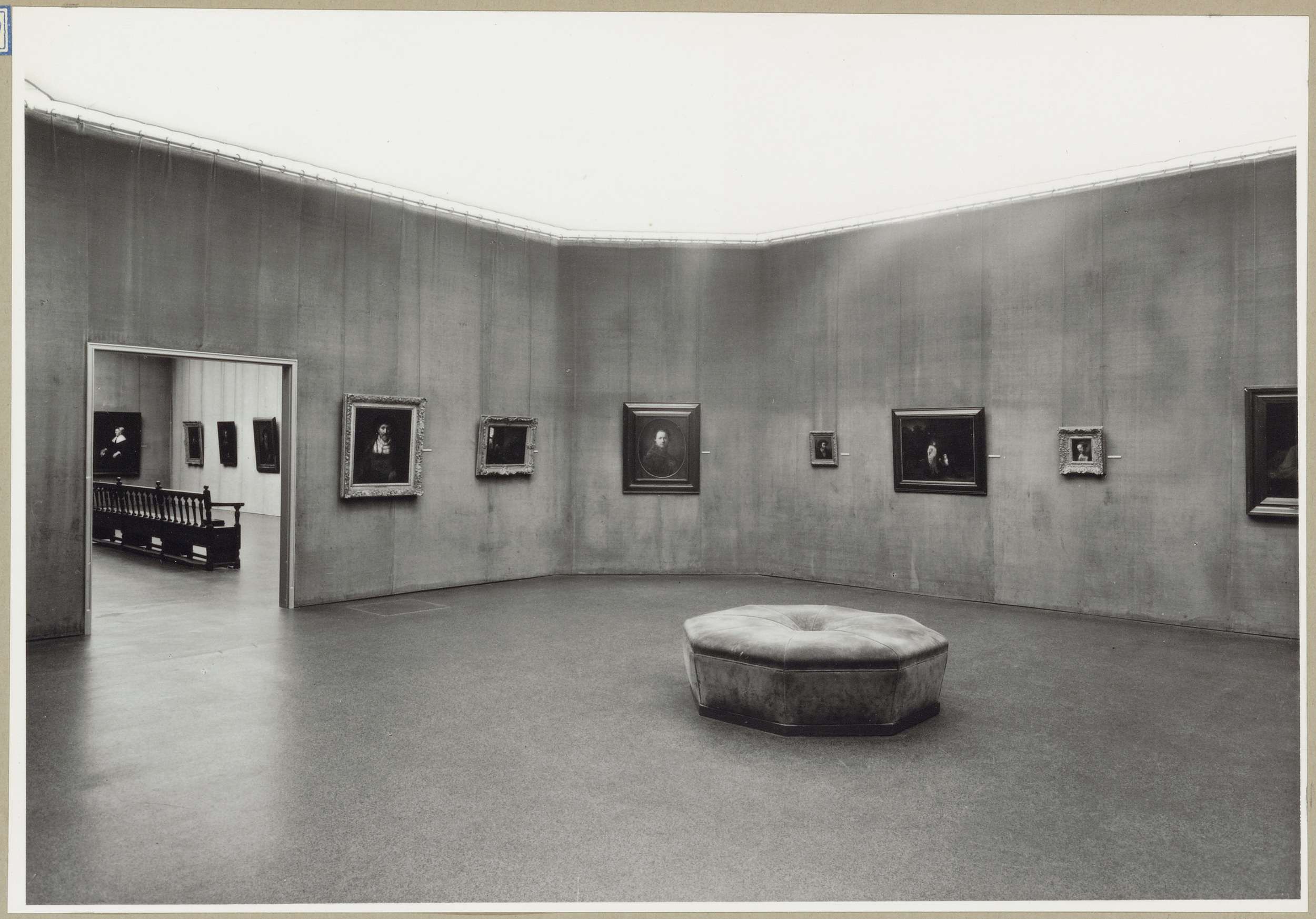 Zaal met zeven schilderijen en een doorkijk naar een andere zaal links