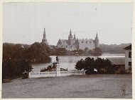 Gezicht op kasteelcomplex aan het water met standbeeld op de voorgrond