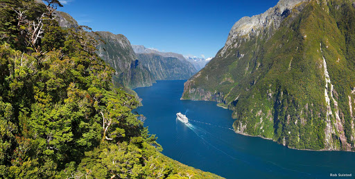 Cruise_ship_through_fjord - Cruise ships are big, but fjords are bigger. Some of these mountains rise to more than 4,900 feet above sea level. Fur seals and penguins play on the rocks with rainforests as a backdrop.