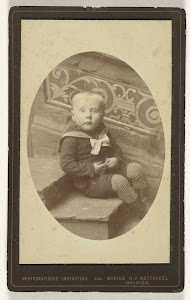 Studioportret van een klein jongetje in matrozenpak zittend op een traptrede