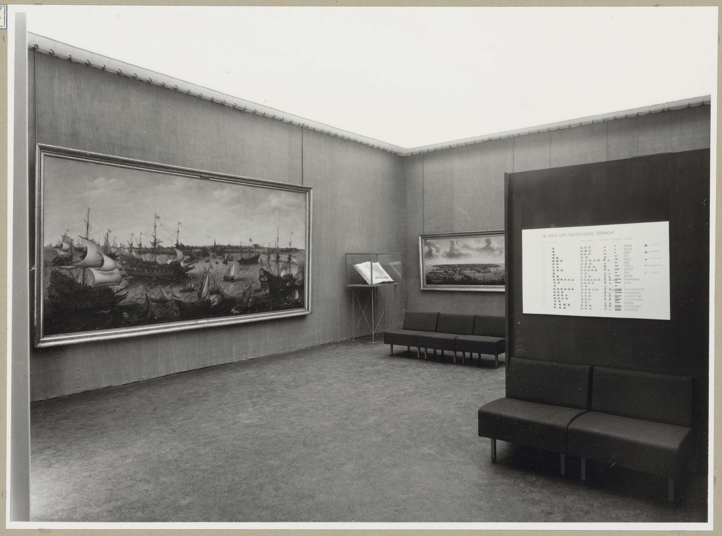 Zaal met schilderijen en een boek in een vitrine