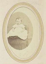 Portret van een baby in een jurk op een fauteuil