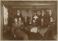 Mannen en vrouwen achter een tafel in een vertrek met balkenplafond