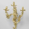 Wandarm van verguld brons met drie uit asymmetrische C- en S-voluten opgebouwde armen.