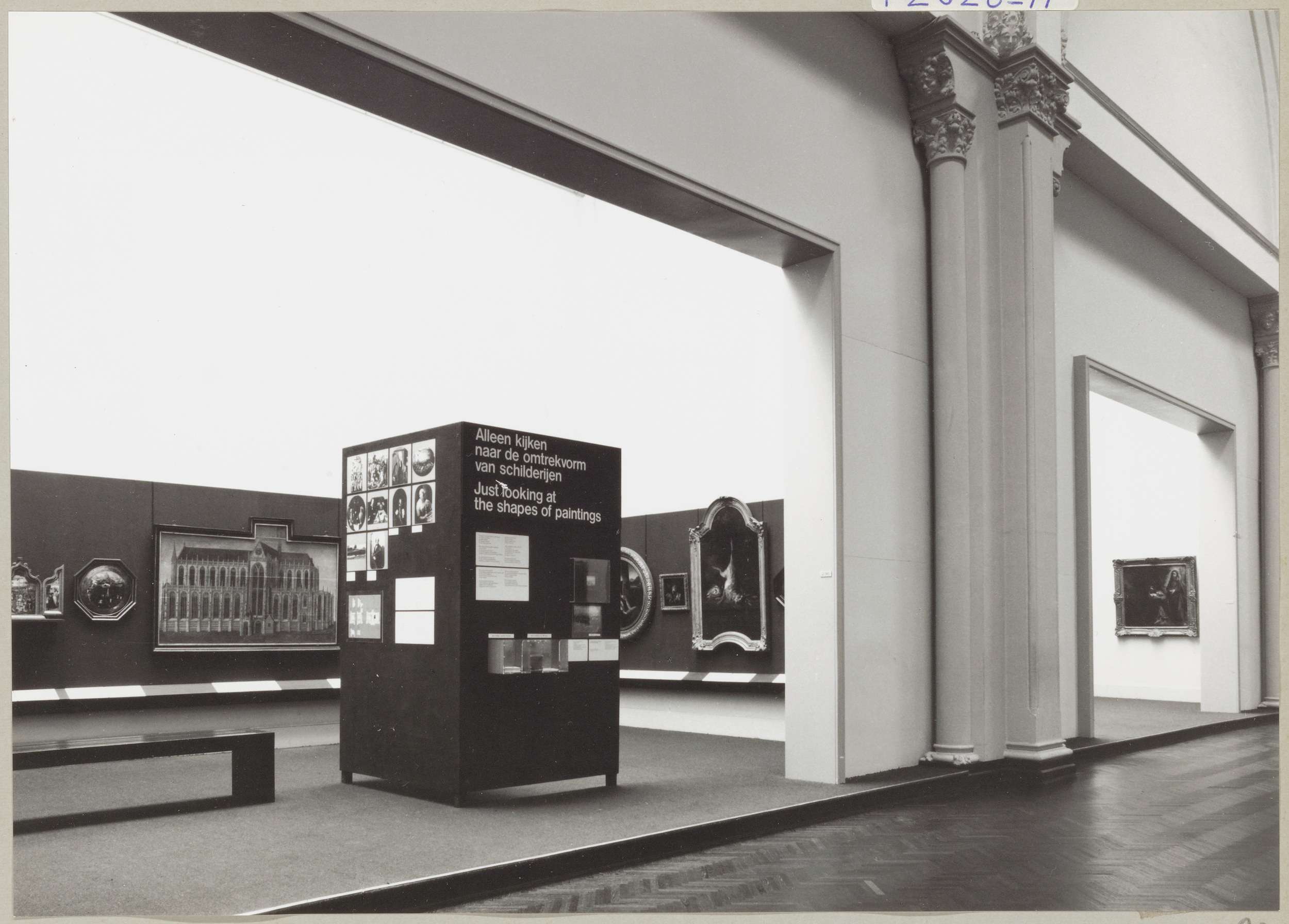 Kabinet van de Eregalerij met diverse objecten, een informatiepaneel met de tentoonstellingstitel, een bank voor bezoekers en zicht op een naastgelegen kabinet