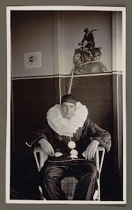 Man verkleed als pierrot, zittend in een rieten stoel