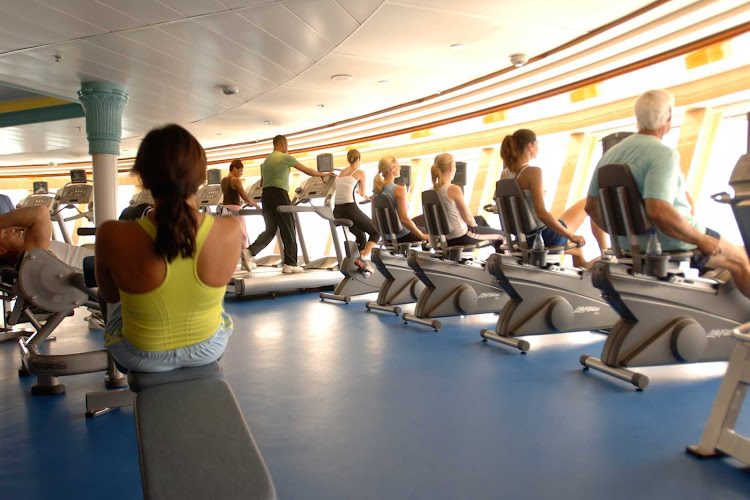Guests work out on cycles, treadmills and other equipment in the Fitness Center aboard a Disney cruise.