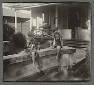 Klaas en Tiny Kleiterp zittend op een muur bij een huis in Singkawang