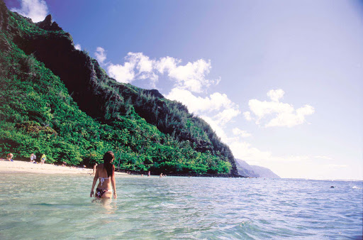 A young woman stands in the surf at Kee Beach, a popular swimming and snorkeling site in Haena on Kauai's north shore.
