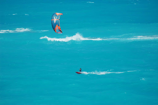 A kite surfer navigates through some gnarly waves along the coast of Bermuda. 