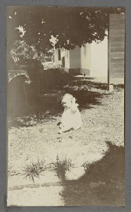 Elf maanden oude baby Tiny Kleiterp zittend op een grasveld in Madjene op Celebes