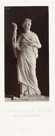 Marmeren beeld van een vrouw in gewaad met een ontblote borst, in haar hand draagt zij een fakkel.