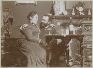 Vrouw bij een man op schoot bij glaasjes wijn in een woonkamer