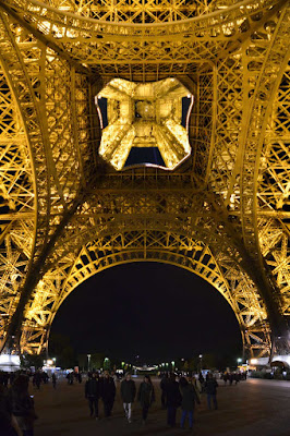 A view of the base of the Eiffel Tower in Paris at night. 