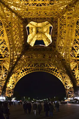 A view of the base of the Eiffel Tower in Paris at night. 