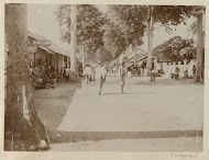 Straatbeeld in Nederlands-Indië met voorbijgangers en winkels
