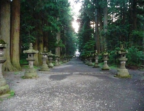 lanternas  de pedras cobertas de musgos alinhadas ao longo da entrada