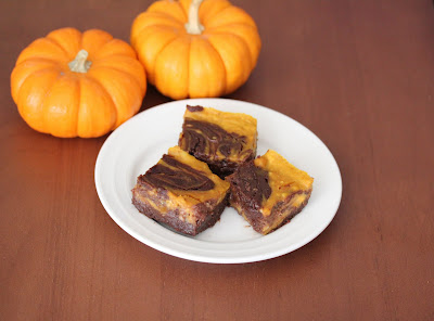 overhead photo of a plate of brownies on a plate with two small pumpkins in the background