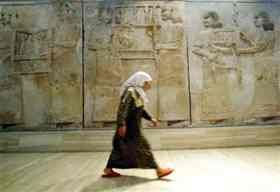An Iraqi woman walks in front of Assyrian mural sculptures July 3, 2003 as the Baghdad museum briefly re-opens to display ancient Nimrud treasures [Credit: Reuters/Radu Sigheti]