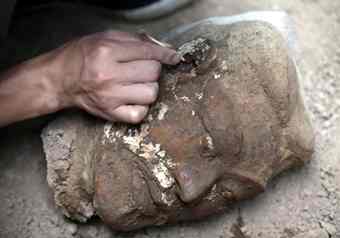 An archaeology staff member applies a special liquid on the ear of a newly found terracotta warrior to help retain the colour of the clay at the excavation site inside the No.1 pit of the Museum of Qin Terracotta Warriors and Horses, on the outskirts of Xi'an, Shaanxi province.