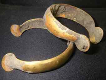 Still coated with earth, the two gold bracelets discovered on road site