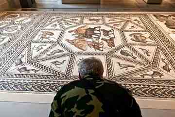 A man leans in to view the Roman mosaic, from Lod, Israel, dating to about 300 A.D., on the floor of the Metropolitan Museum of Art.