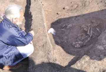 Archaeologist Borisov shown looking at the 8000-year-old skeleton. Photo by Bulphoto 
