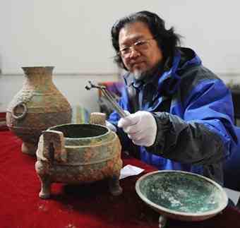 Liu Daiyun, a Shaanxi Provincial Archeological Institute official, picks up a piece of bone from a recently discovered bronze vessel in Xi'an, northwest China's Shaanxi Province, Dec. 10, 2010. A 2,400-year old bronze vessel containing soup with bones has been discovered recently in a tomb excavated in Xi'an. The vessel is 20 centimeters tall and has a 24.5 centimeters diameter. The archeologists also unearthed a bronze pot containing an odorless liquid, which may be ancient wine. 