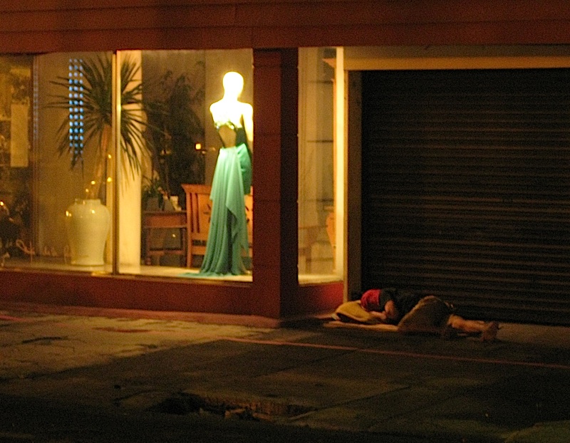 homeless person sleeping in front of a fashion designer's atelier